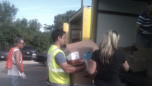 Daniel loading up a donation of food for a family waiting in their car. The donation includes dry staples, vegetables, meat, bread, and a pastry